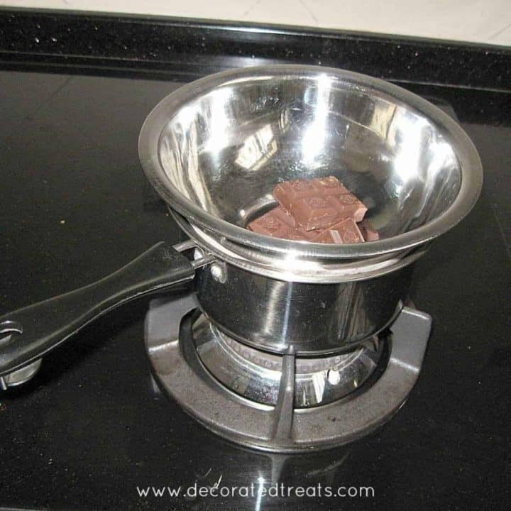 A pot on a stove with a bowl of chocolate on top