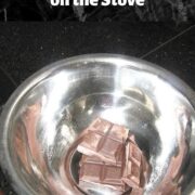 A stainless steel bowl with chopped chocolate over a pot of water on the stove.