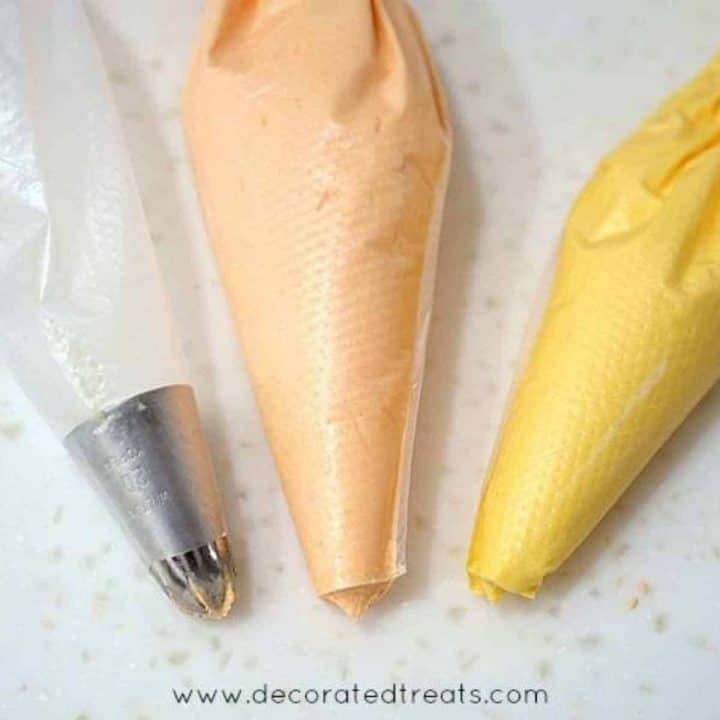 3 piping bag, one with a tip attached, 2 with orange and yellow icing without any tips