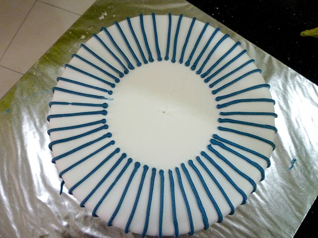 Blue lines piped all around a round cake