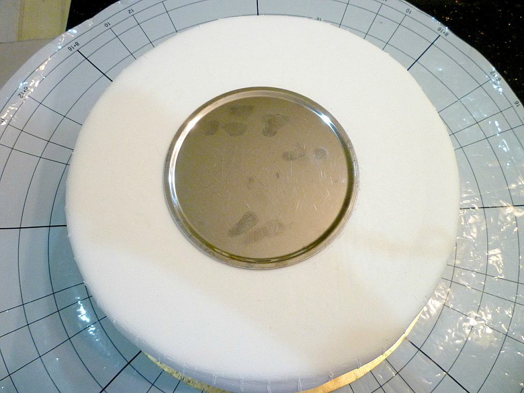 A round steel plate on a white fondant covered cake