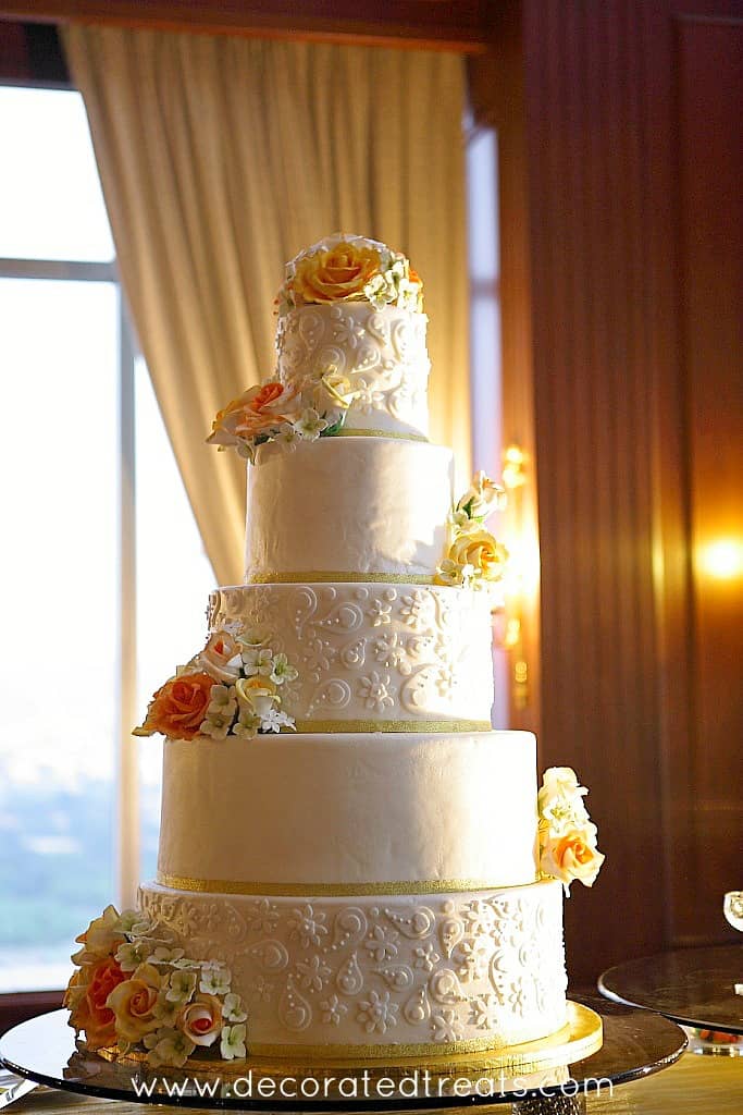 Um bolo de casamento de 5 camadas decorado em laranja e amarelo