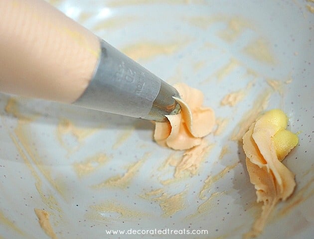 Piping orange buttercream into a small bowl