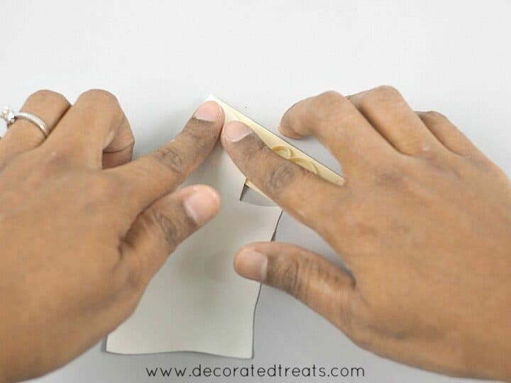 Using fingers to press on a piece of gum paste on a letter cutter