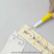 Using a needle tool to remove the gum paste from the alphabet cutter.
