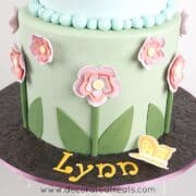 A round floral cake with the name Lynn on the cake board.
