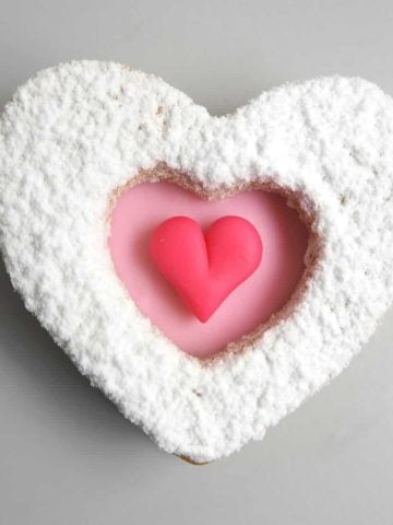 A heart shaped cookie decorated in pink heart and icing sugar