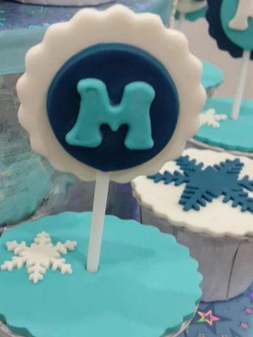 Cupcake covered in turquoise with a letter "m" topper in blue, white and turquoise.