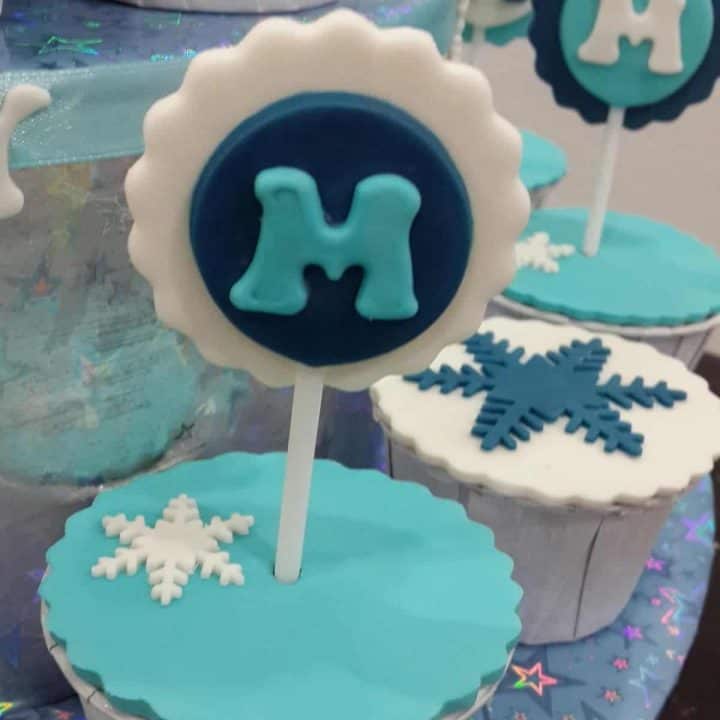 Cupcake covered in turquoise with a letter "m" topper in blue, white and turquoise