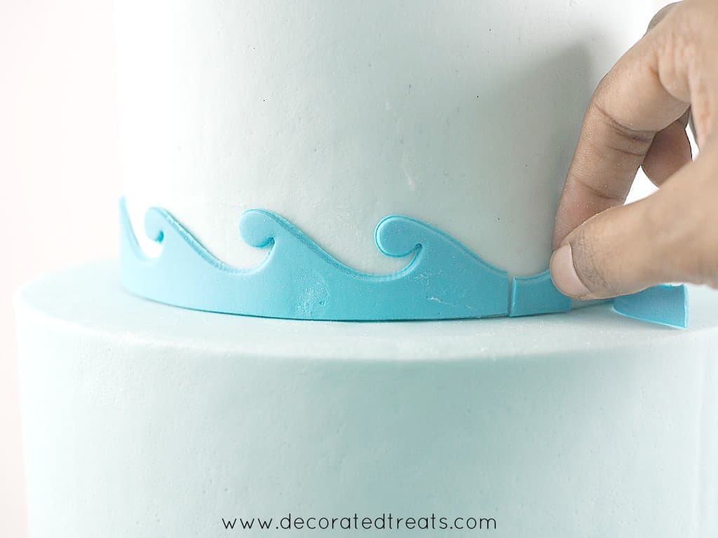 Adjusting fondant waves border on a cake