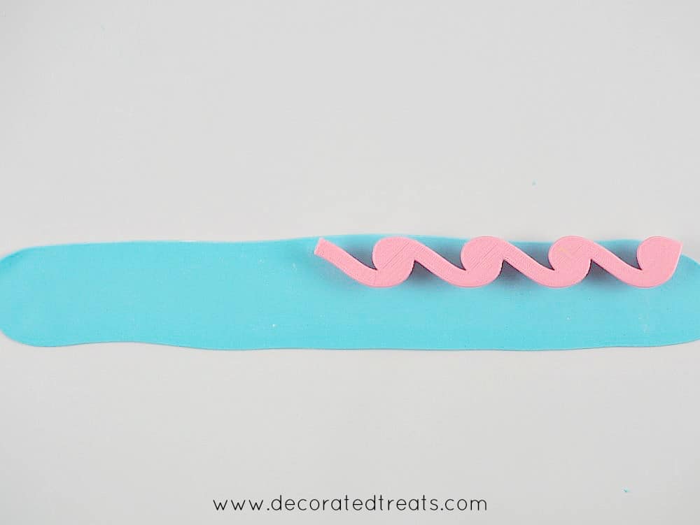 Pink fondant waves cutter on a strip of light blue fondant