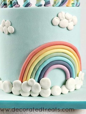 A rainbow cake decorated with fondant clouds.
