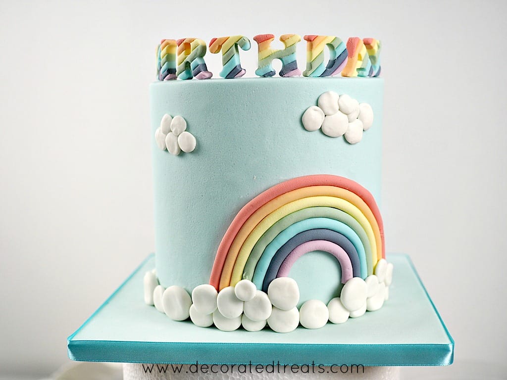 A rainbow cake decorated with fondant clouds
