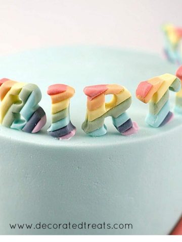 Rainbow colored fondant letters on a cake.
