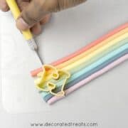 Using a sugar craft knife to cut the fondant on which in a letter H cutter.