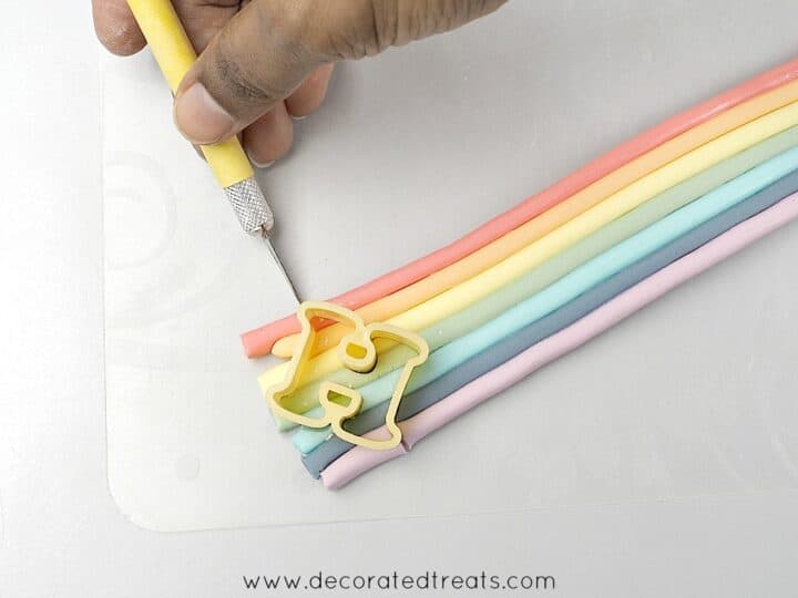 Using a sugar craft knife to cut the fondant on which in a letter H cutter