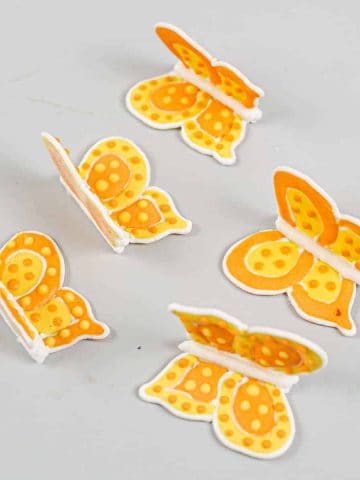 Orange and yellow royal icing butterflies against a grey background