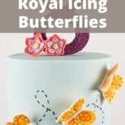 A poster of a blue cake with yellow and orange royal icing butterflies.