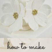 2 white gum paste flowers on the corner of a cake.