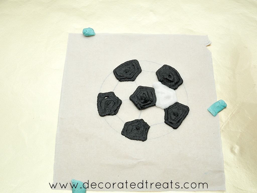 Royal icing soccer ball on a parchment square