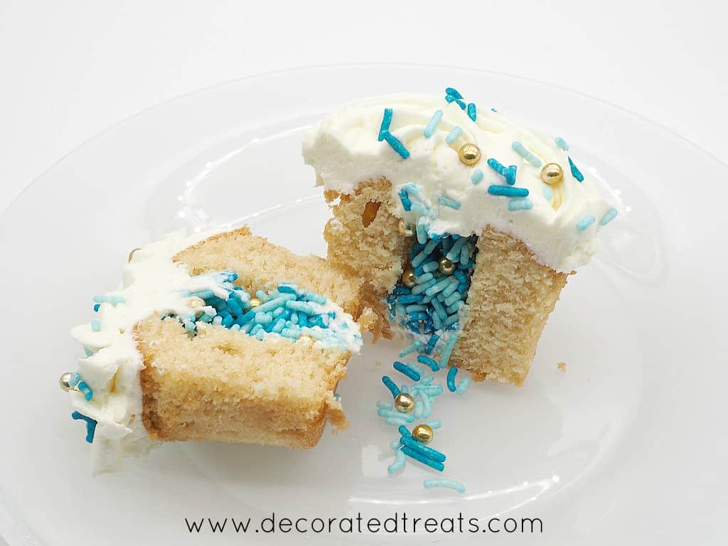 A cupcake cut into half, with blue and gold sprinkles in the center. Cupcake is topped with white frosting
