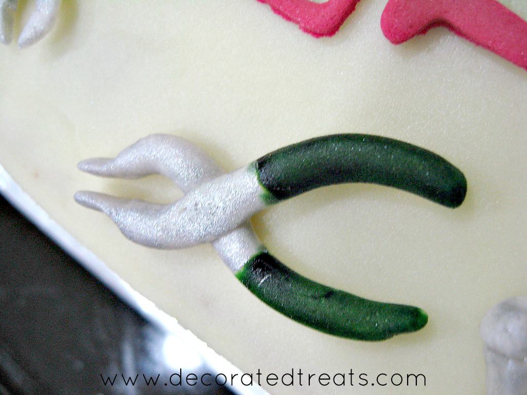 Fondant pliers in silver and green, on a cake