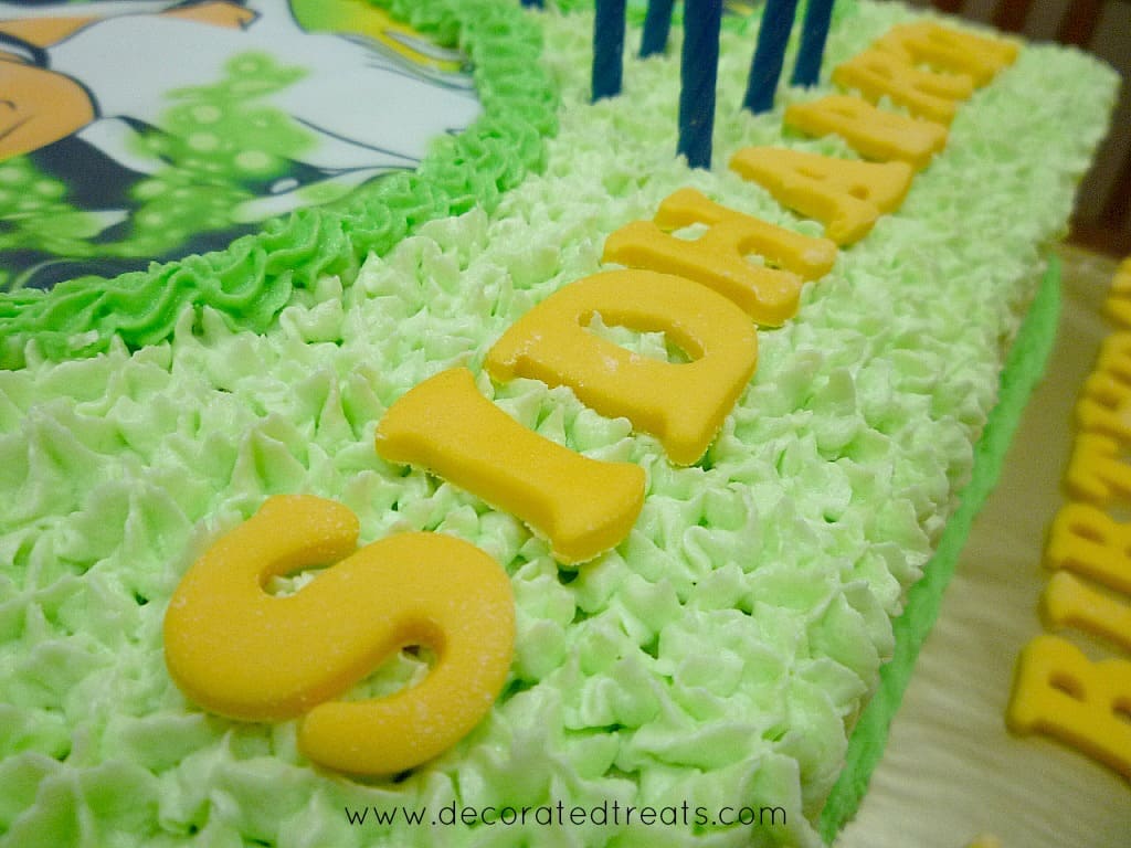 Yellow fondant alphabets on a green buttercream cake