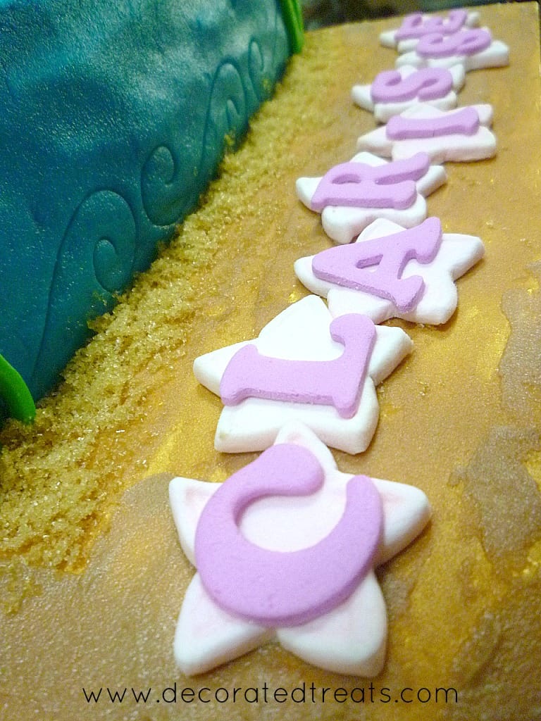 Fondant letters on star cutouts on a cake board.