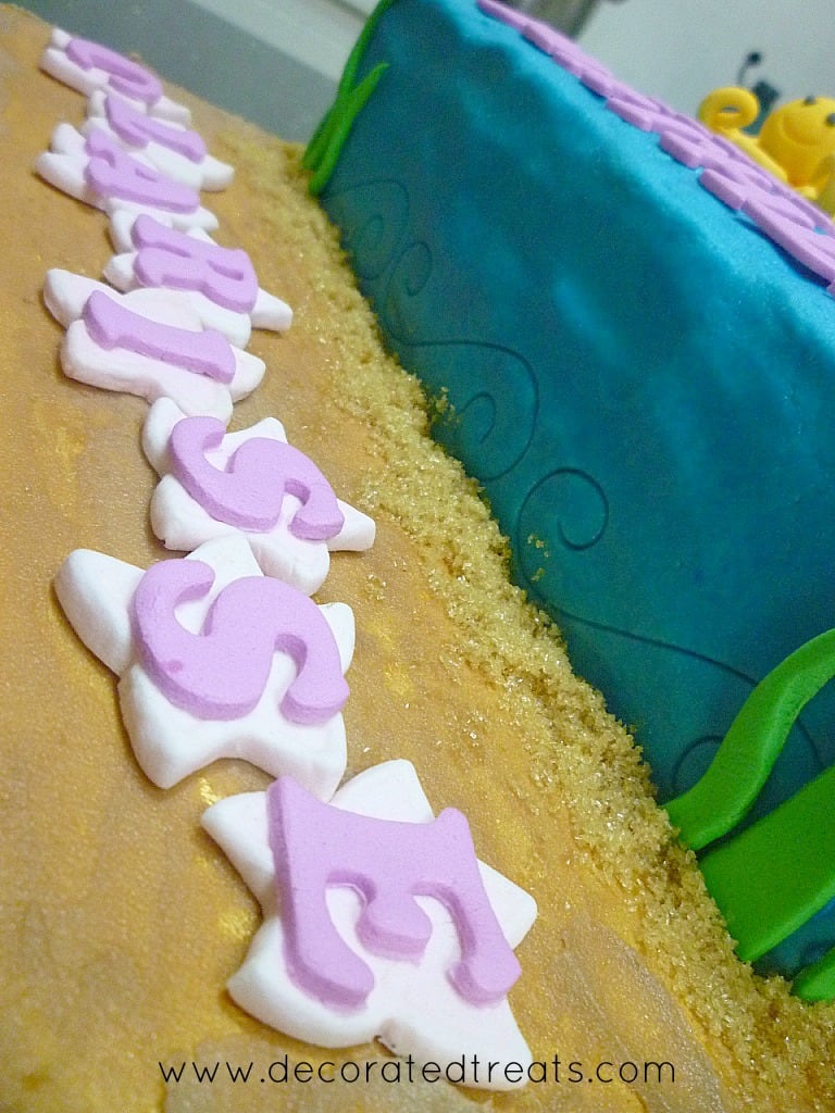 Fondant letters on star cutouts on a cake board.