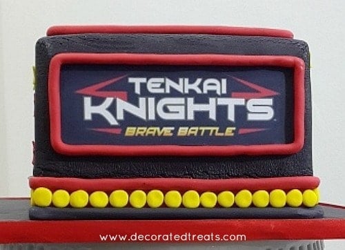 The front of a black square cake with Tenkai Knights edible image
