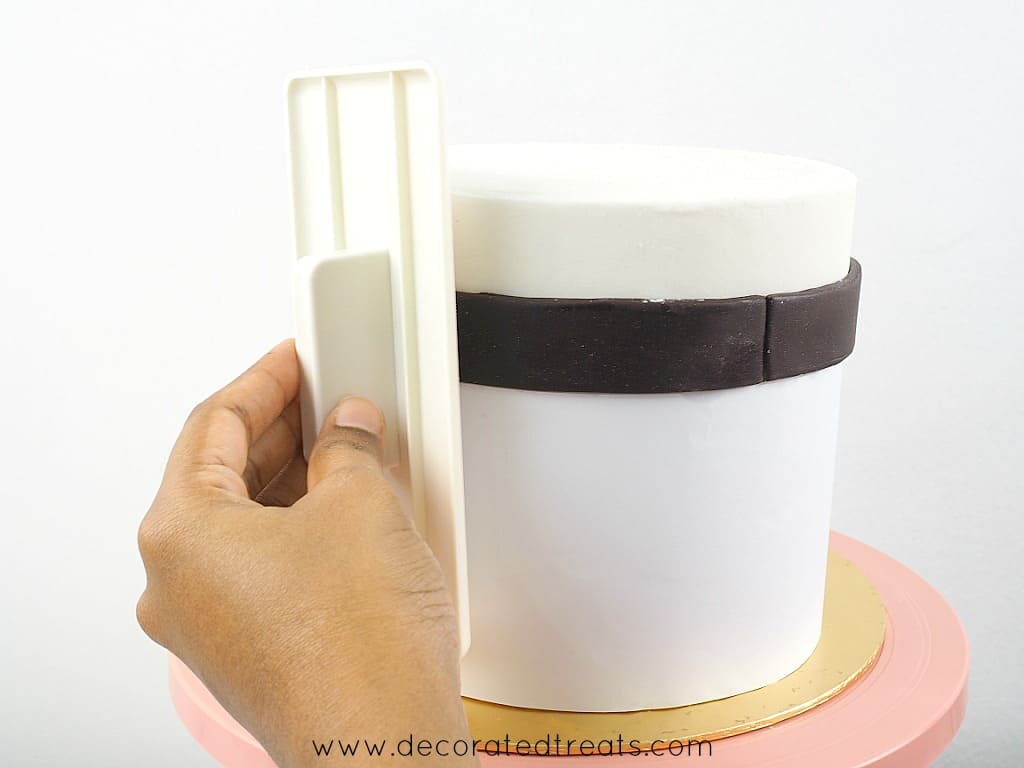 Using a fondant smoother to smooth a cake