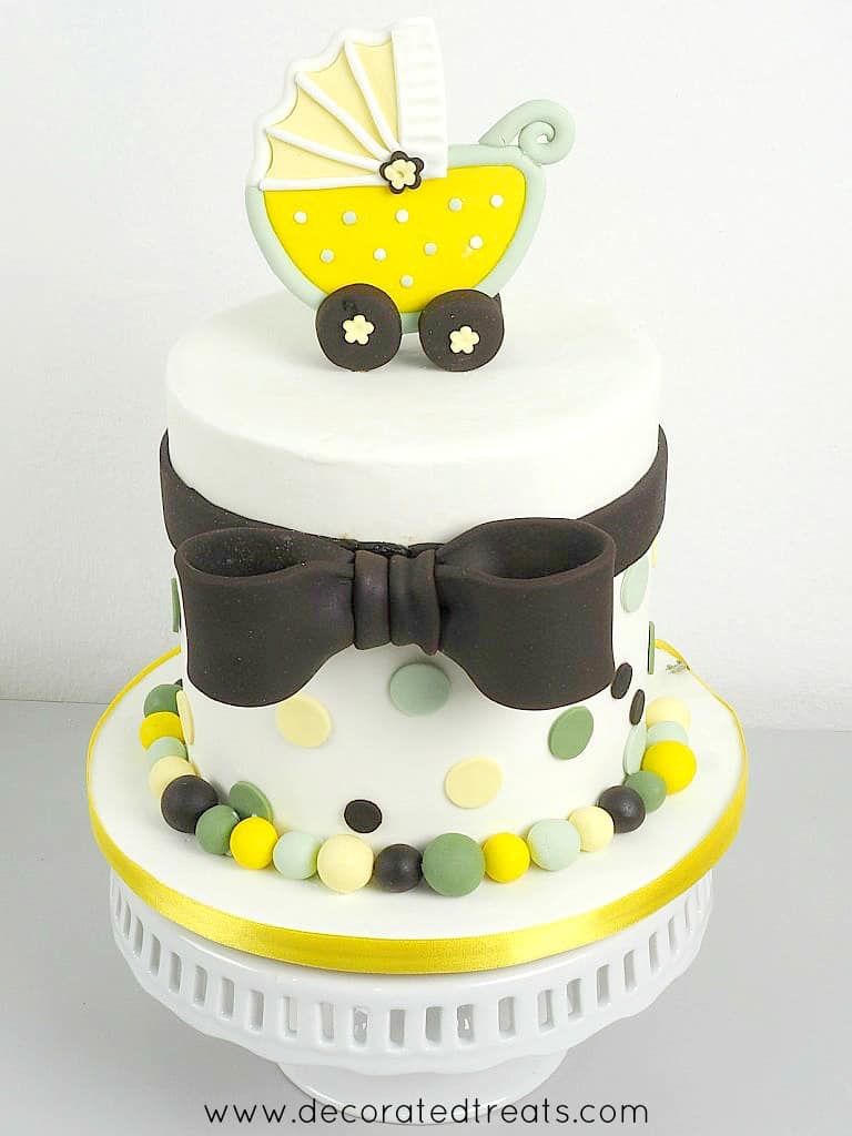 A round baby shower cake with a yellow buggy cake topper