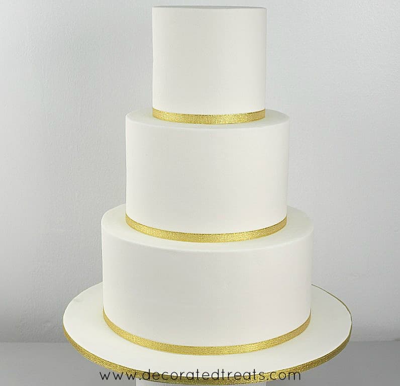 3 tier white cake with gold ribbon border