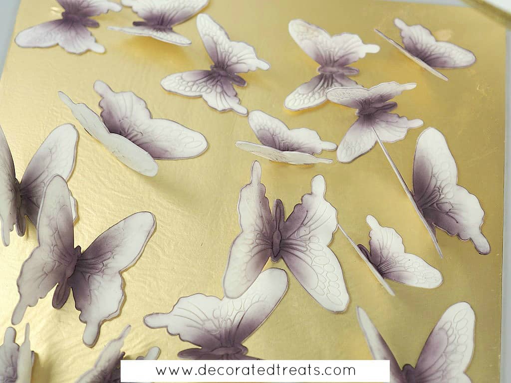 Gum paste butterflies dusted in dark purple on a gold cake board