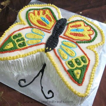 A butterfly shaped cake decorated in yellow, green, red and blue
