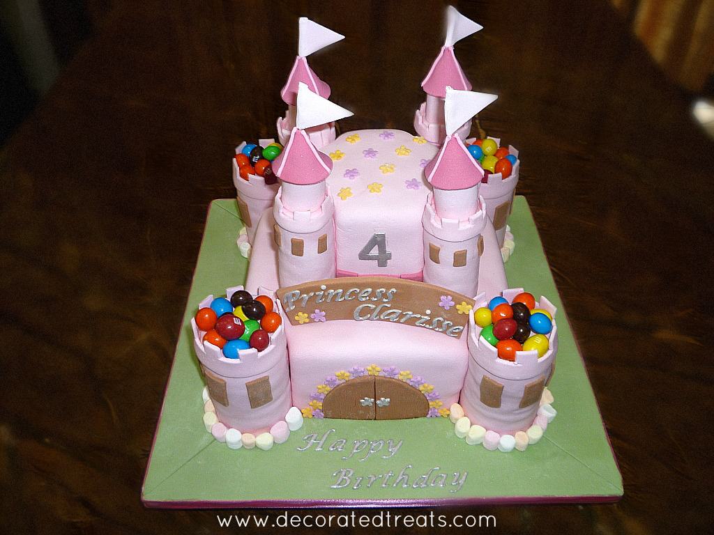 A two tier pink castle cake decorated with M&Ms and marshmallows