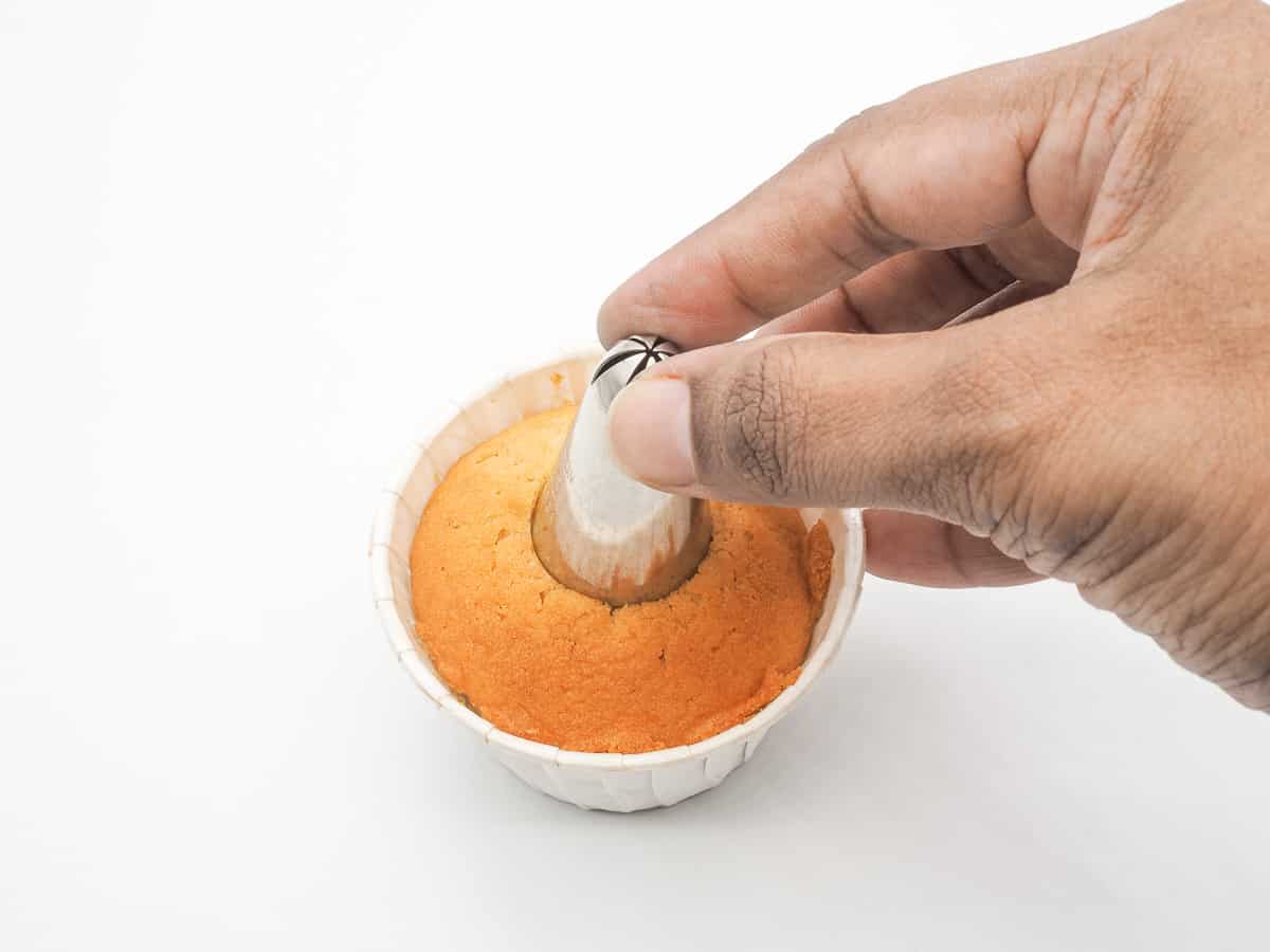 Using a piping tip to press in the center of a cupcake.