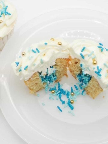 Cupcake cut into half, with the center filled with blue and gold sprinkles.