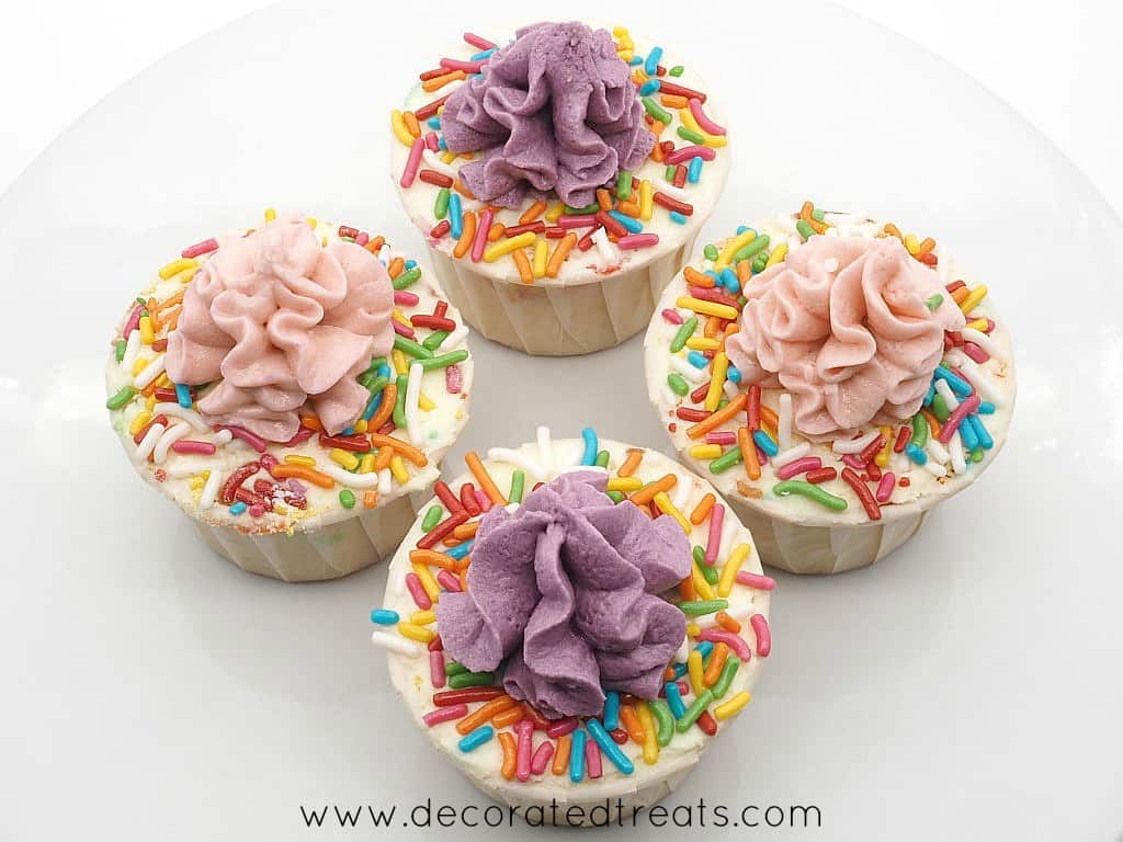 4 cupcakes decorated in buttercream and sprinkles