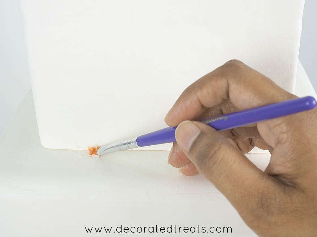 Using a small brush to brush a cake border