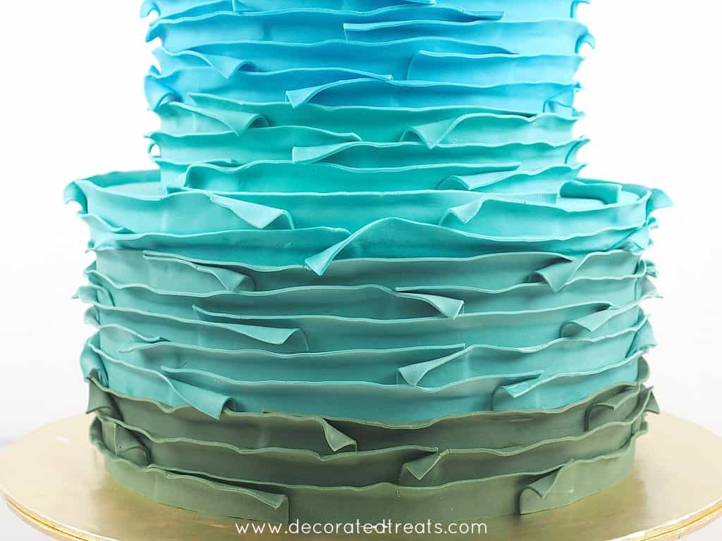 Bottom tier of a cake covered in green fondant strips
