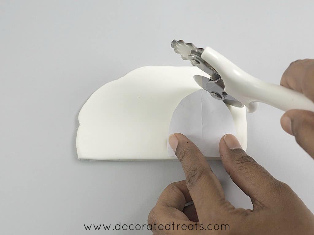 Cutting fondant with pizza cutter, guided by paper template