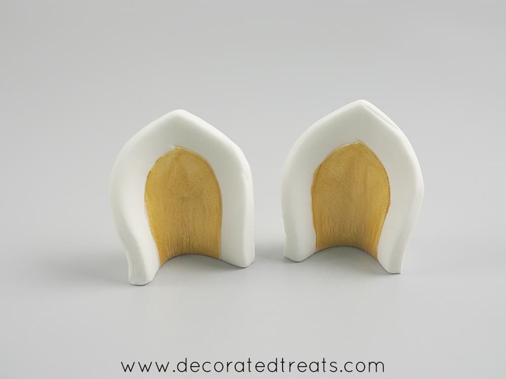 2 fondant ears with centers painted in gold