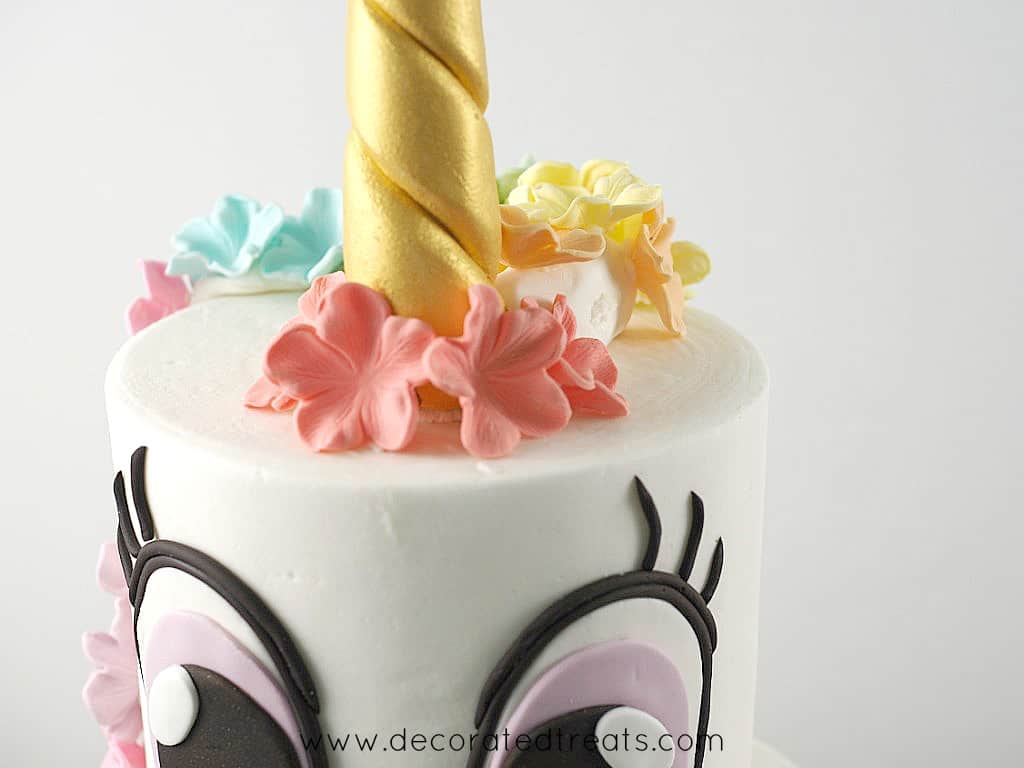 Front of a unicorn cake decorated with simple sugar blossoms in fondant