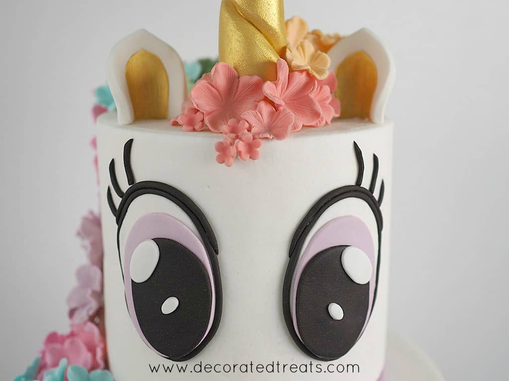 Large fondant eyes on the front of a unicorn cake