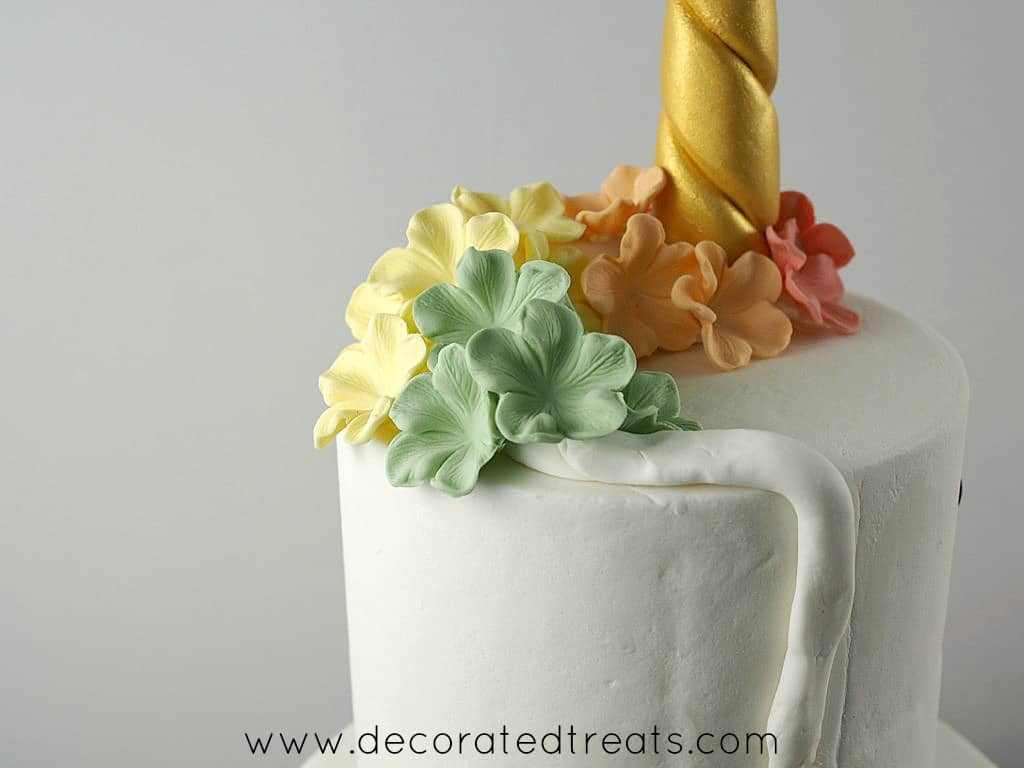 Red, orange, yellow and green lowers on top of a unicorn cake
