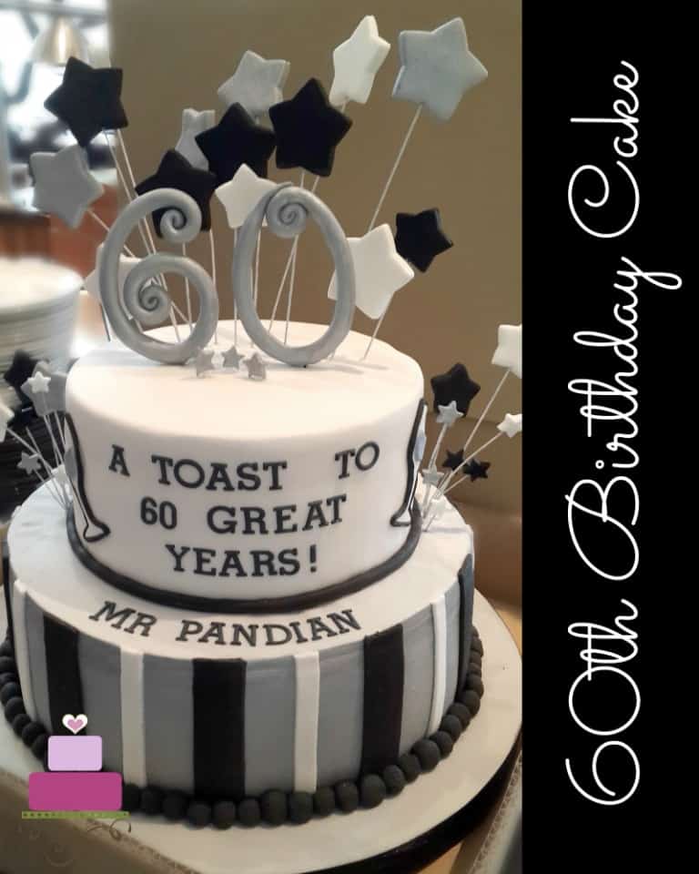2 tier cake decorated in silver, black and white with a large number 60 topper and matching stars