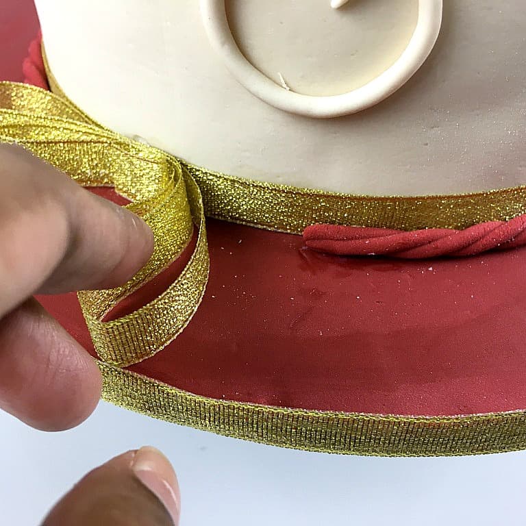Showing a gold ribbon around the base of a cake.