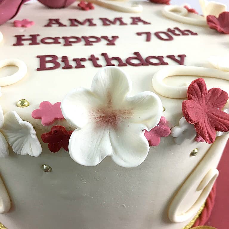 Fondant flowers in white and maroon on a cake.