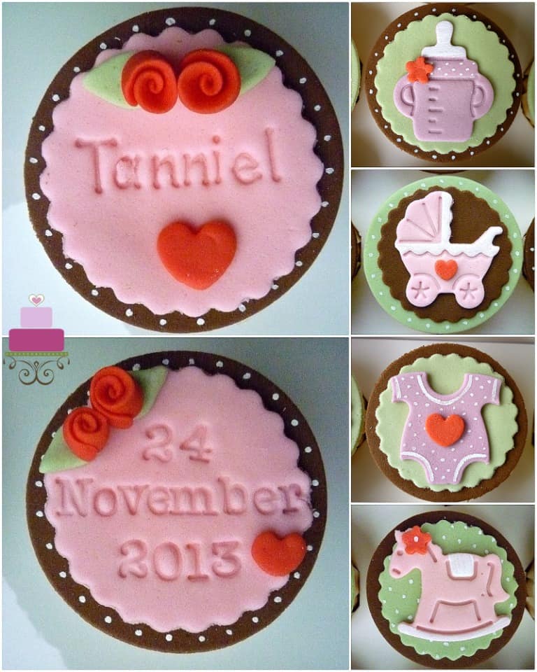 4 cupcakes with a stroller, bodysuit, rocking horse and baby bottle fondant 2d deco on each. 2 more cupcakes are decorated with the baby name and date of birthday and tiny red fondant roses